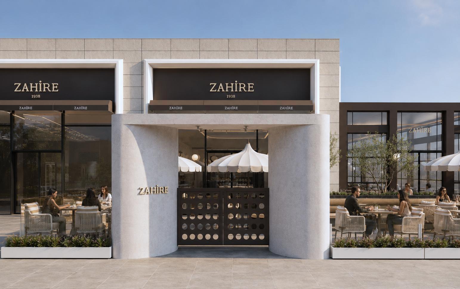 Zahire 1938 Rota Kafe cephesi — kavisli krem taş portal, altın marka bandı, delikli bronz kapı ve önündeki teras